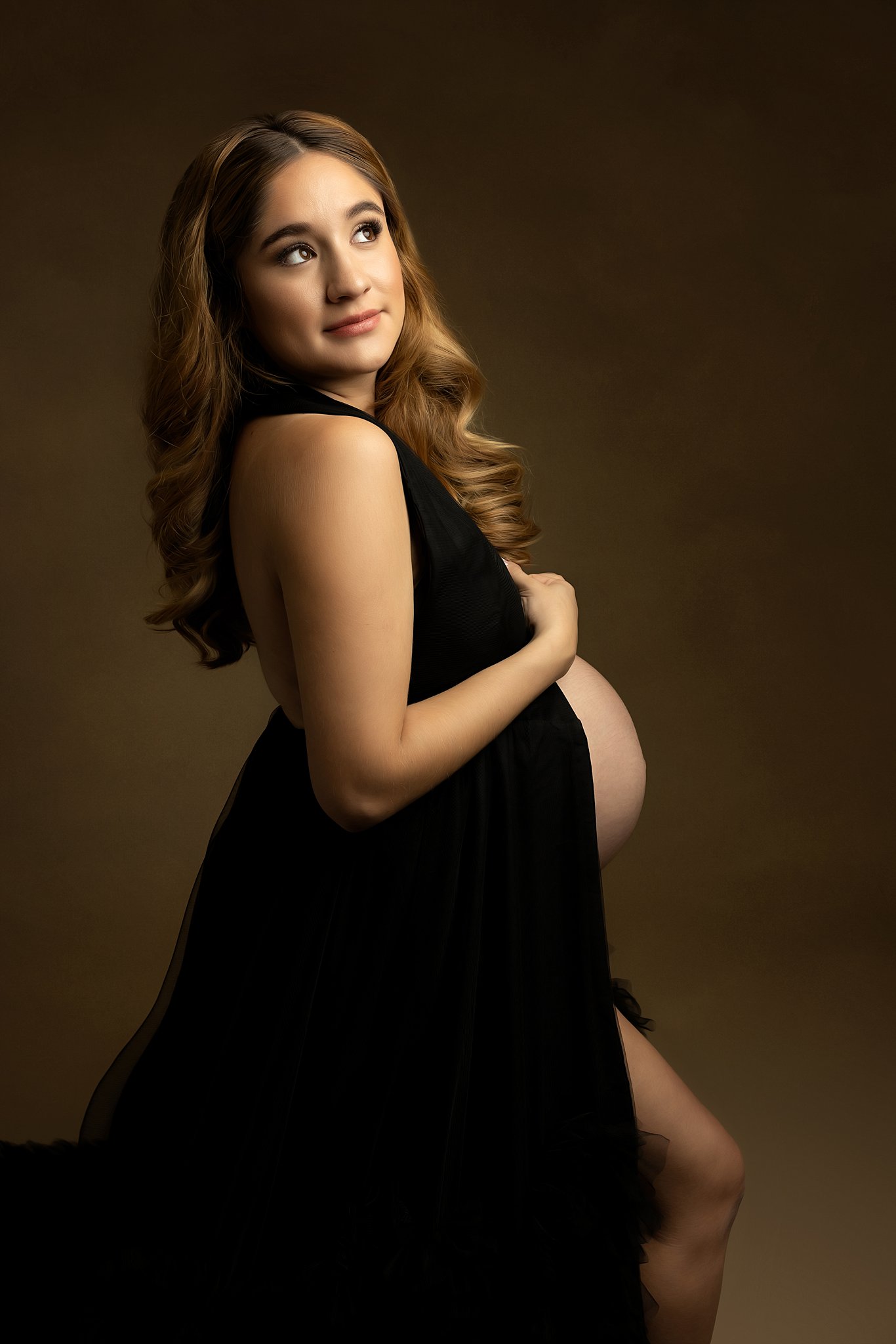 Mother to be stands in a studio wearing a black maternity gown charleston birth place