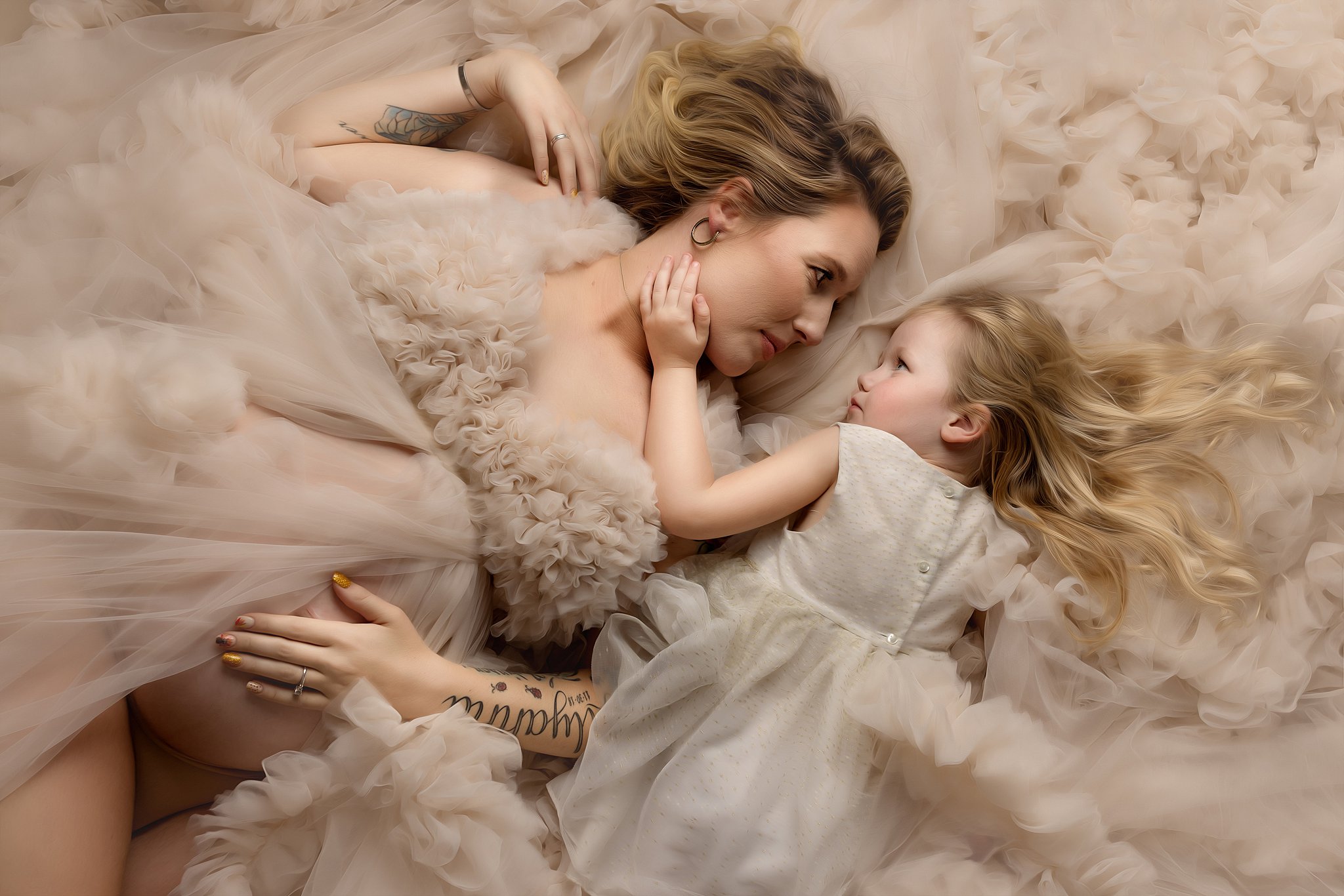 Mother to be lays on a bed of velour from her maternity gown with her daughter charleston doulas