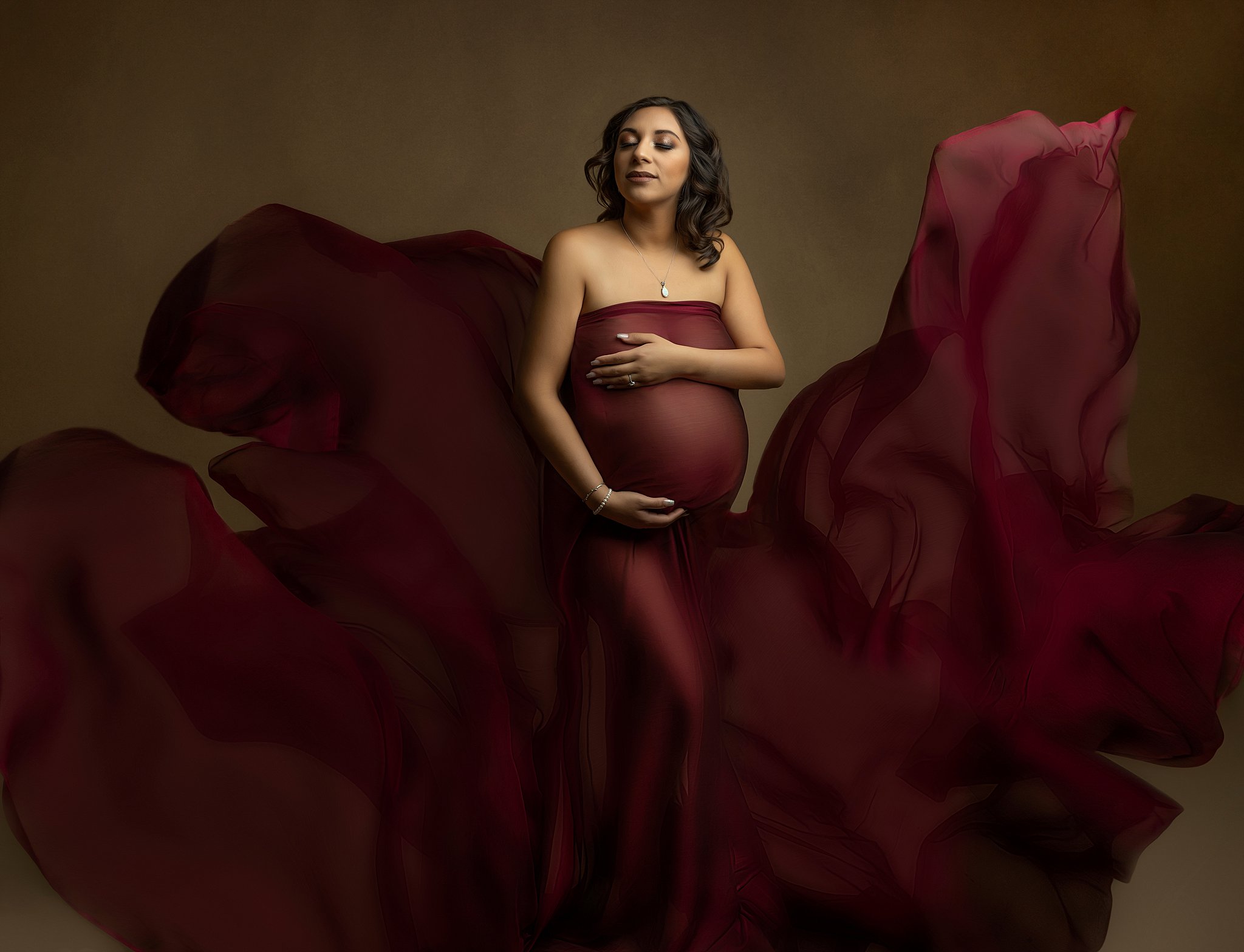 A mother to be stands in a studio wearing a purple maternity gown that is flowing all around her prenatal yoga charleston